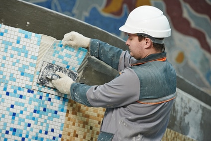 Pisciniste de illiCO Travaux posant une mosaïque dans un bassin de natation.