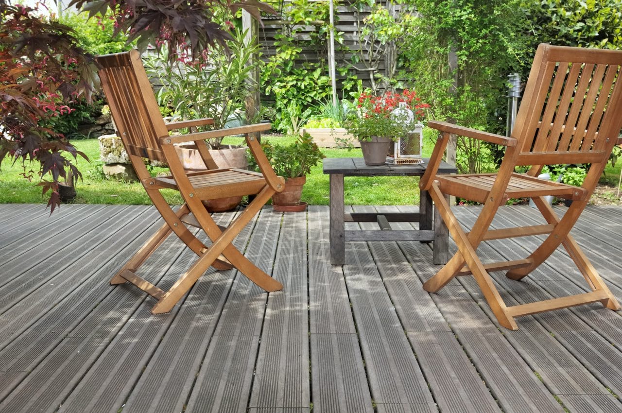 chaises et table sur terrasse en bois donnant sur jardin